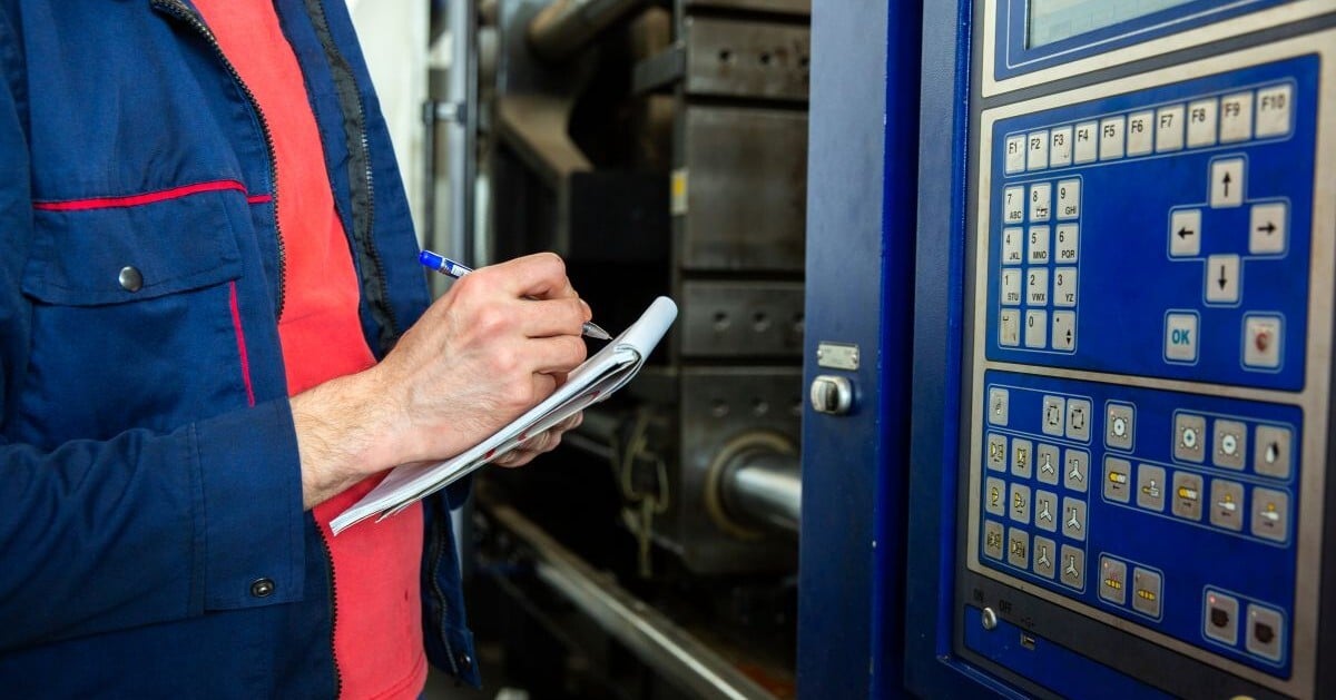 Equipment appraiser inspecting industrial machinery and documenting equipment specifications