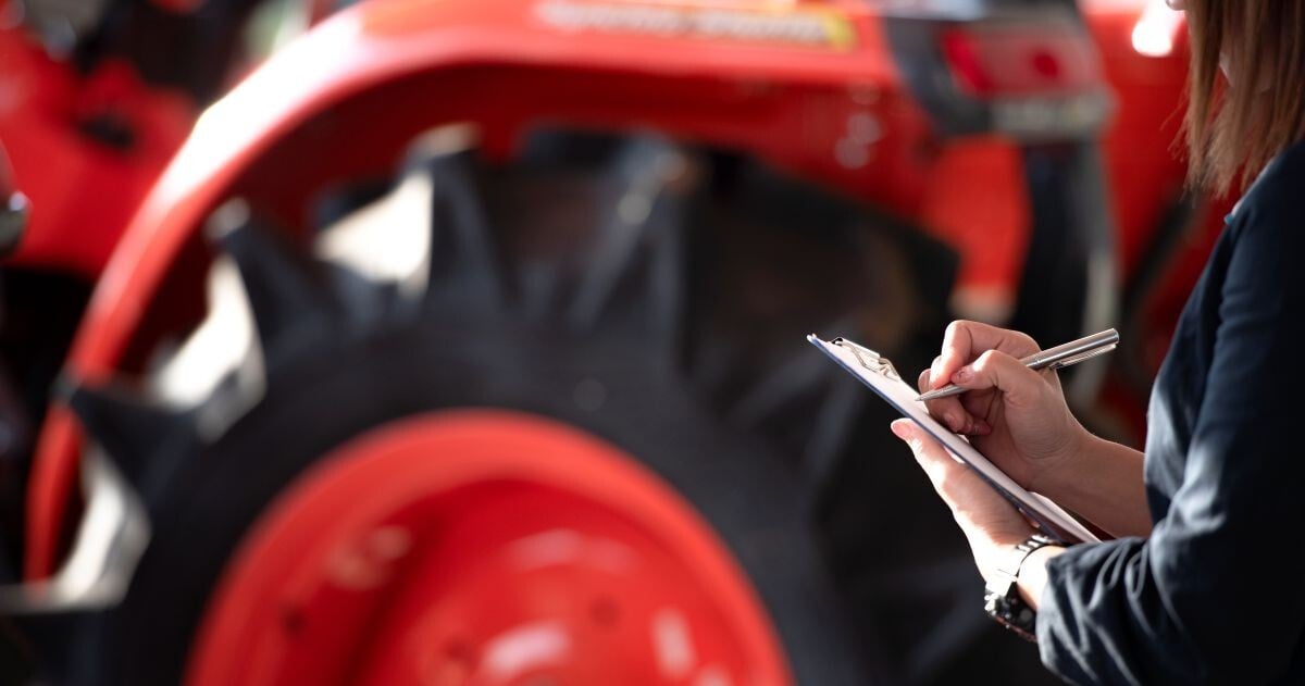 Equipment appraiser documenting tractor information during an equipment appraisal.